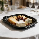 Plateau traiteur noir 45 cm garni de fromages, raisin et noix sur une table de banquet