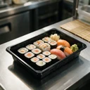 Plateau à sushi 169 × 119 mm en PET noir garni d'un assortiment de makis et de nigiris, en cuisine japonaise