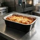 Plat aluminium noir 780 ml garni de lasagnes sur un plan de travail de cuisine professionnelle
