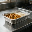 Barquette aluminium 825 ml garnie d'un curry et de riz sur un plan de travail de cuisine